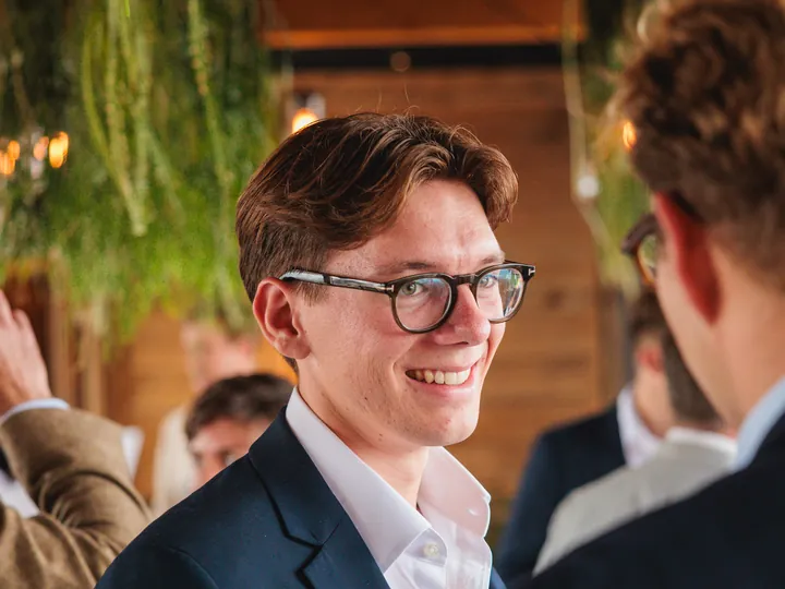 A smiling guest in glasses chatting at an evening party