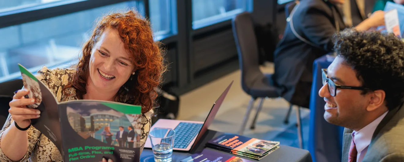A visitor smiling as she reads a brochure at a QS fair