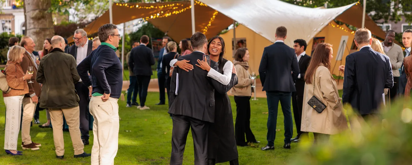 Guests mingling on a lawn at summer drinks under a white canopy