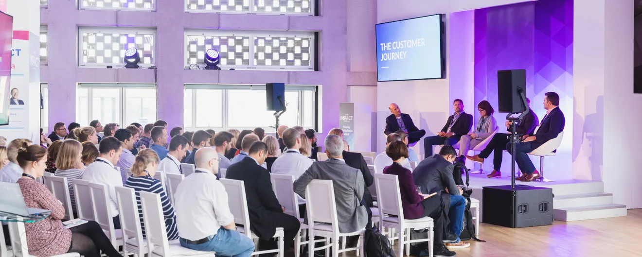 A panel discussion in front of a full audience in a bright event space