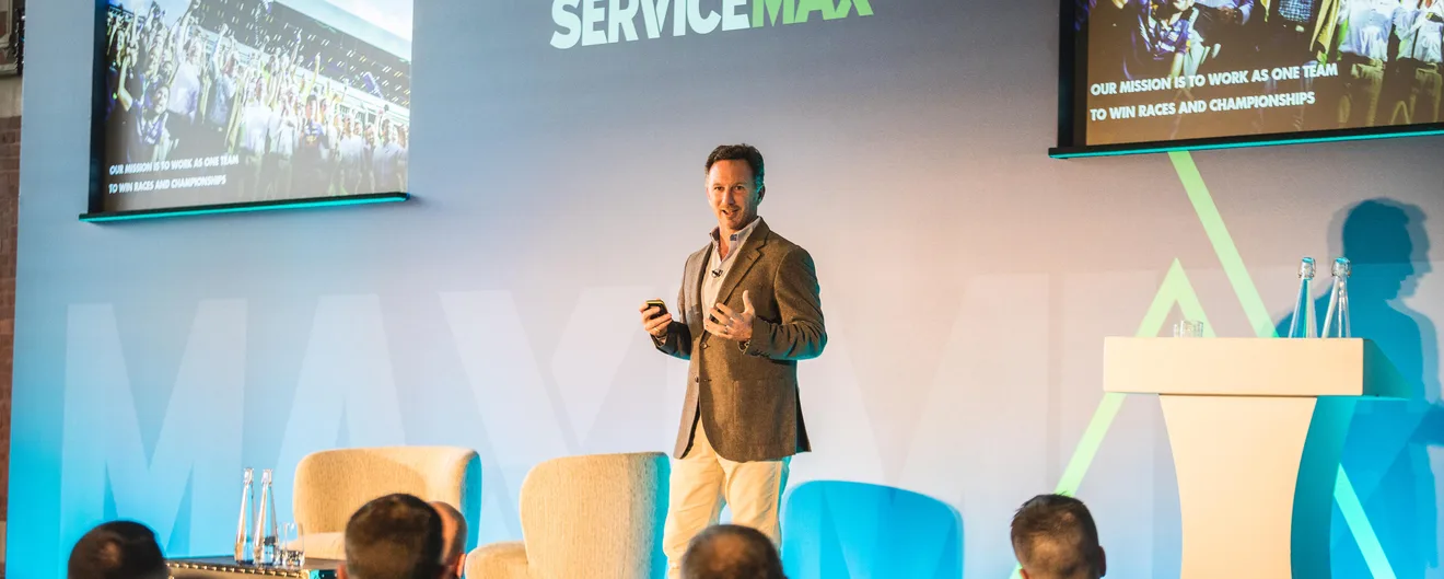 A speaker presenting on stage at a ServiceMax conference